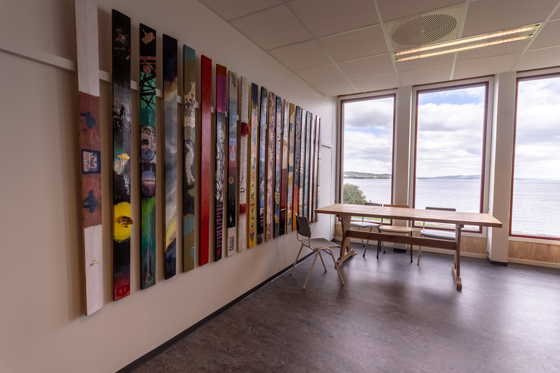 Kunstrom med utstilling av avlange malerier på rekke