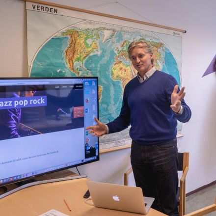 Økonomileder Willy Flermoen på Musikkfolkehøgskoen Viken står foran storskjerm