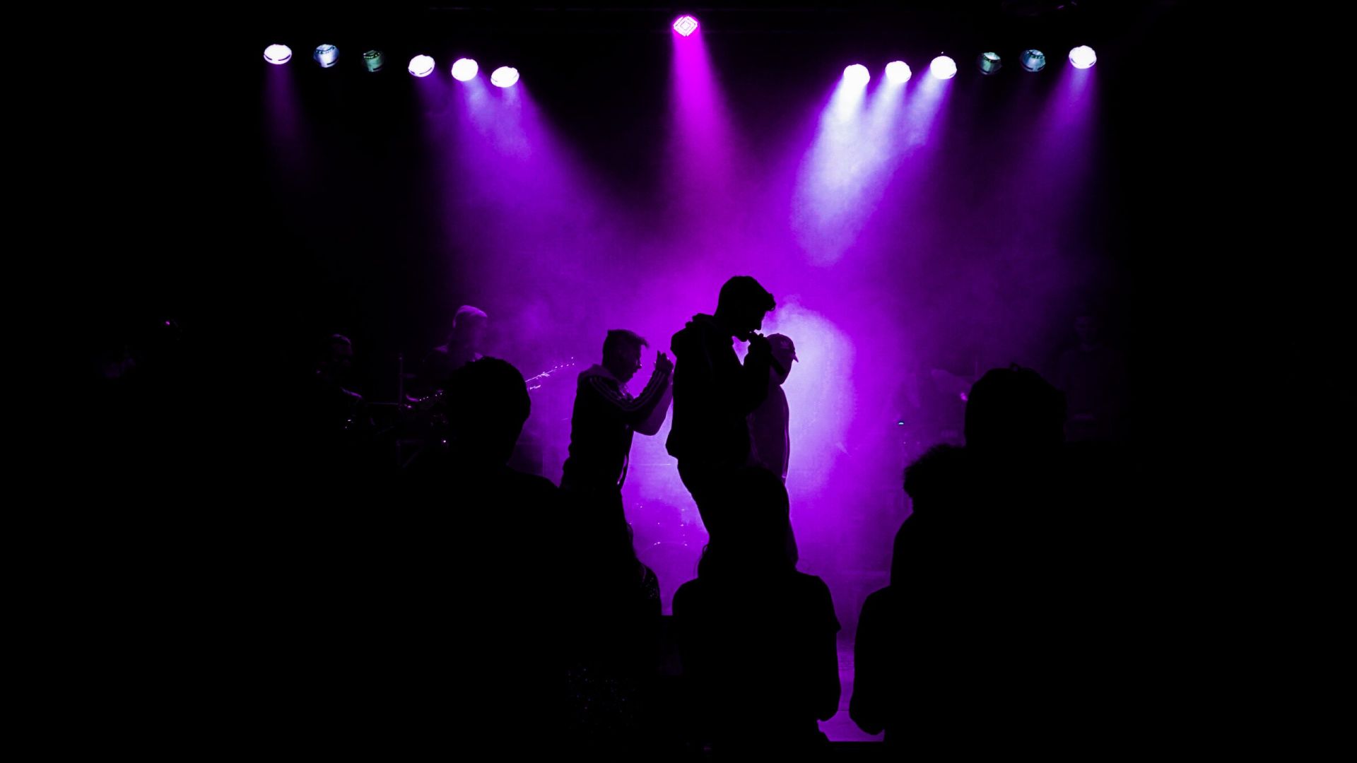 Siluetter av artister på scene i lilla lys